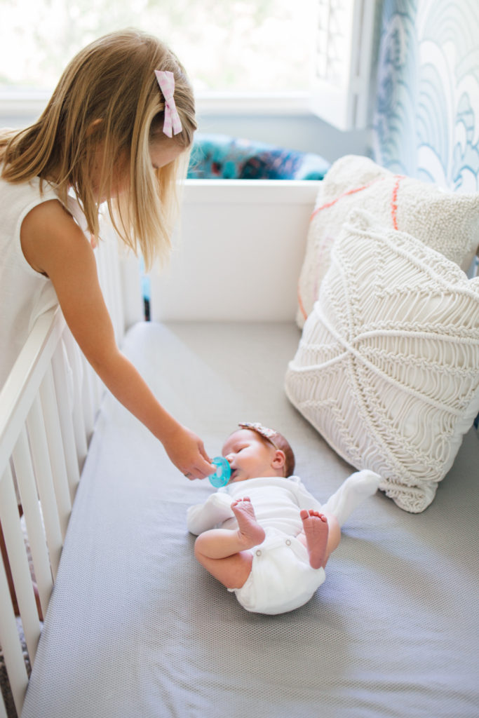 An older child in a nursery interacting affectionately with a newborn
