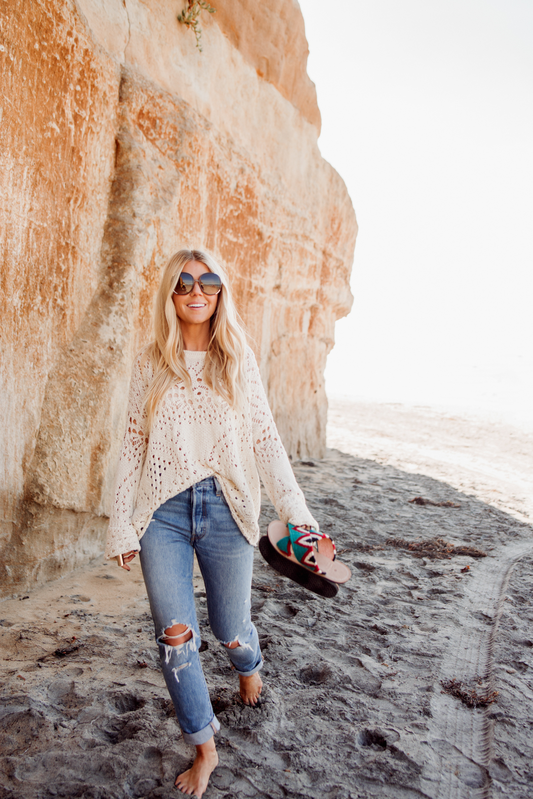 Lisa Allen of Salty Lashes wearing a cream Free People sweater with Levi 501's, tribal sandals, and Chloe sunglasses in Solana Beach California for Easter Weekend Sales