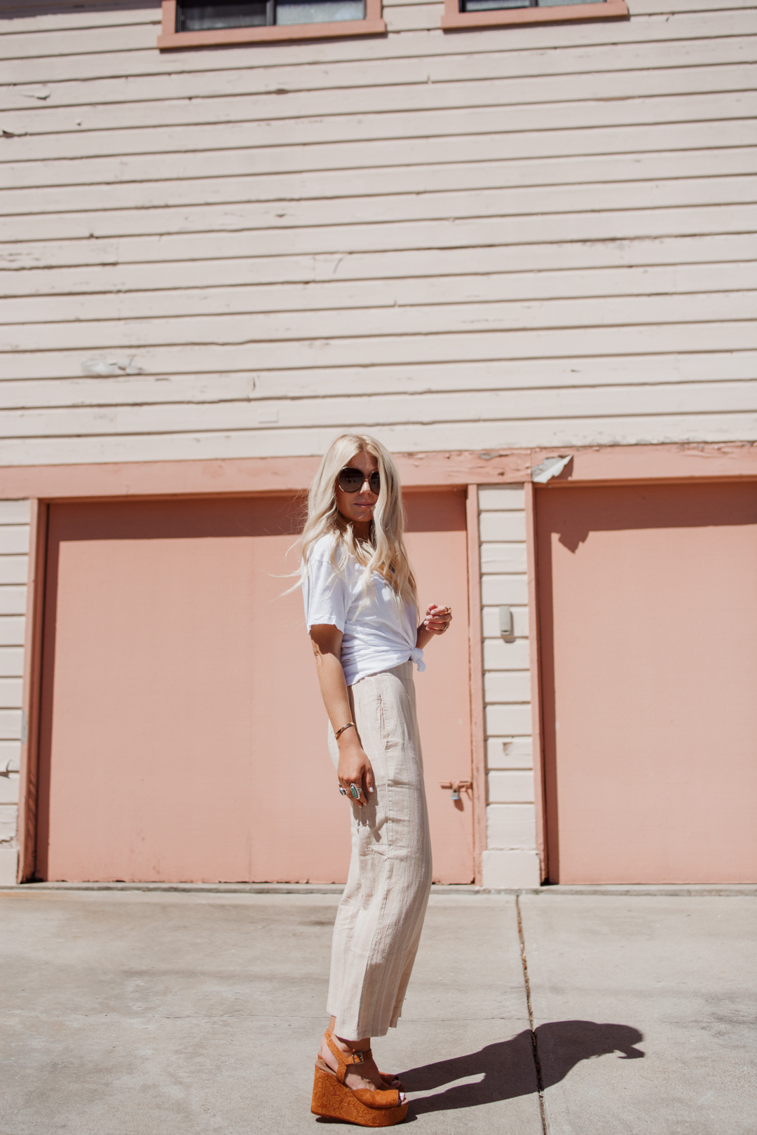 Lisa Allen of Salty Lashes styles a white Current/Elliott tee with UO cropped pants and Chloe Myrtle sunglasses while strolling in Encinitas, California.