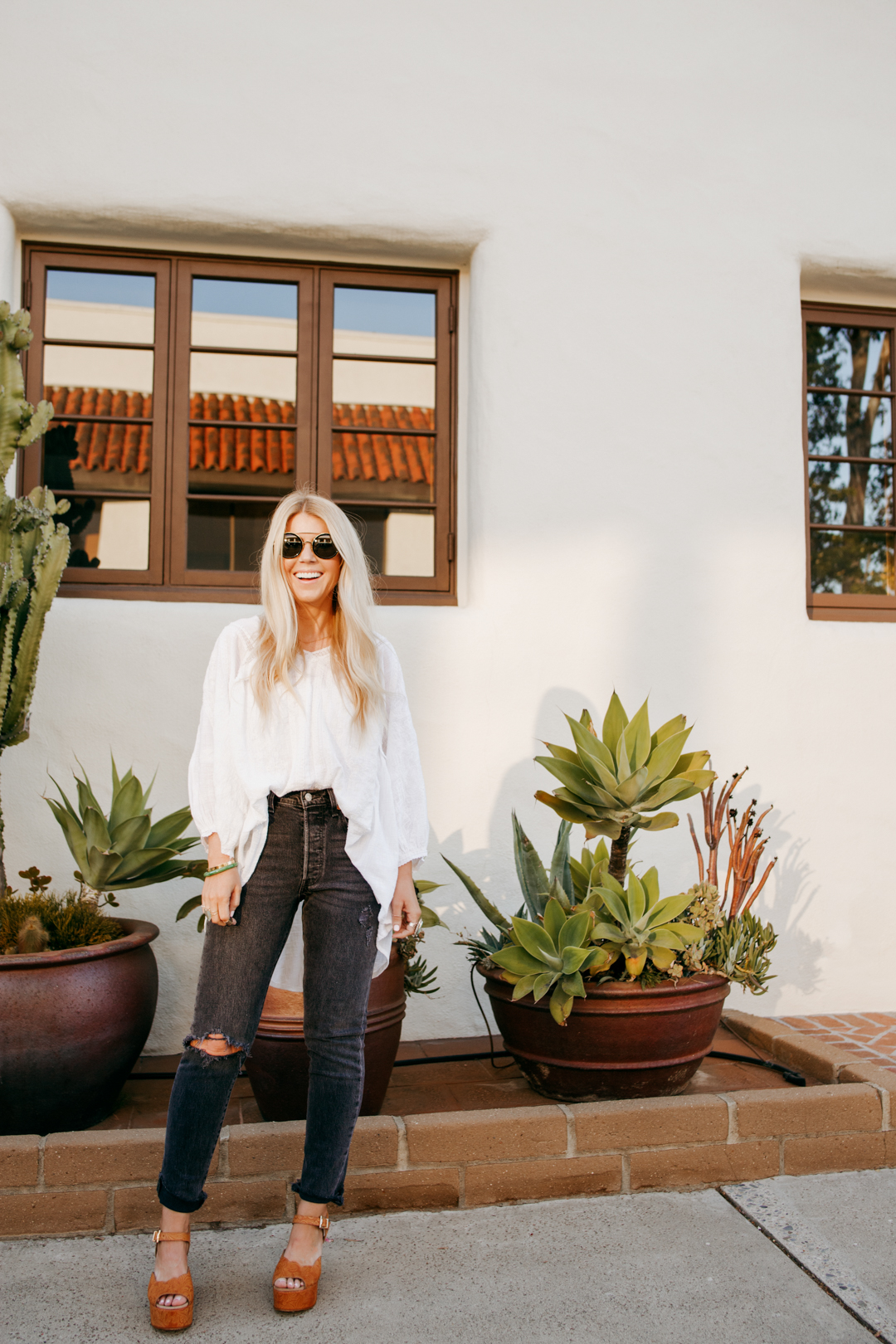 lisa allen of salty lashes wearing a white free people tunic with black levi's, free people platforms and wild fox sunglasses 