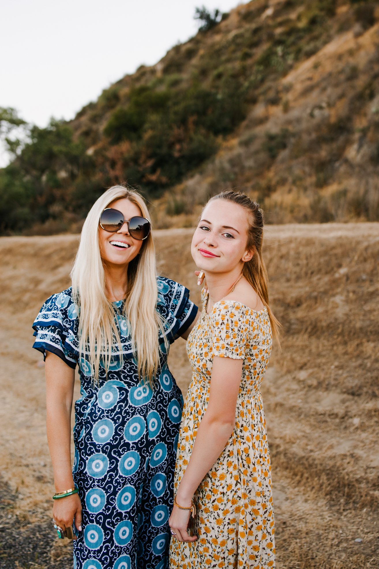 lisa allen of salty lashes wearing a blue patterned jumpsuit, and poppy wearing a yellow floral smocked dress