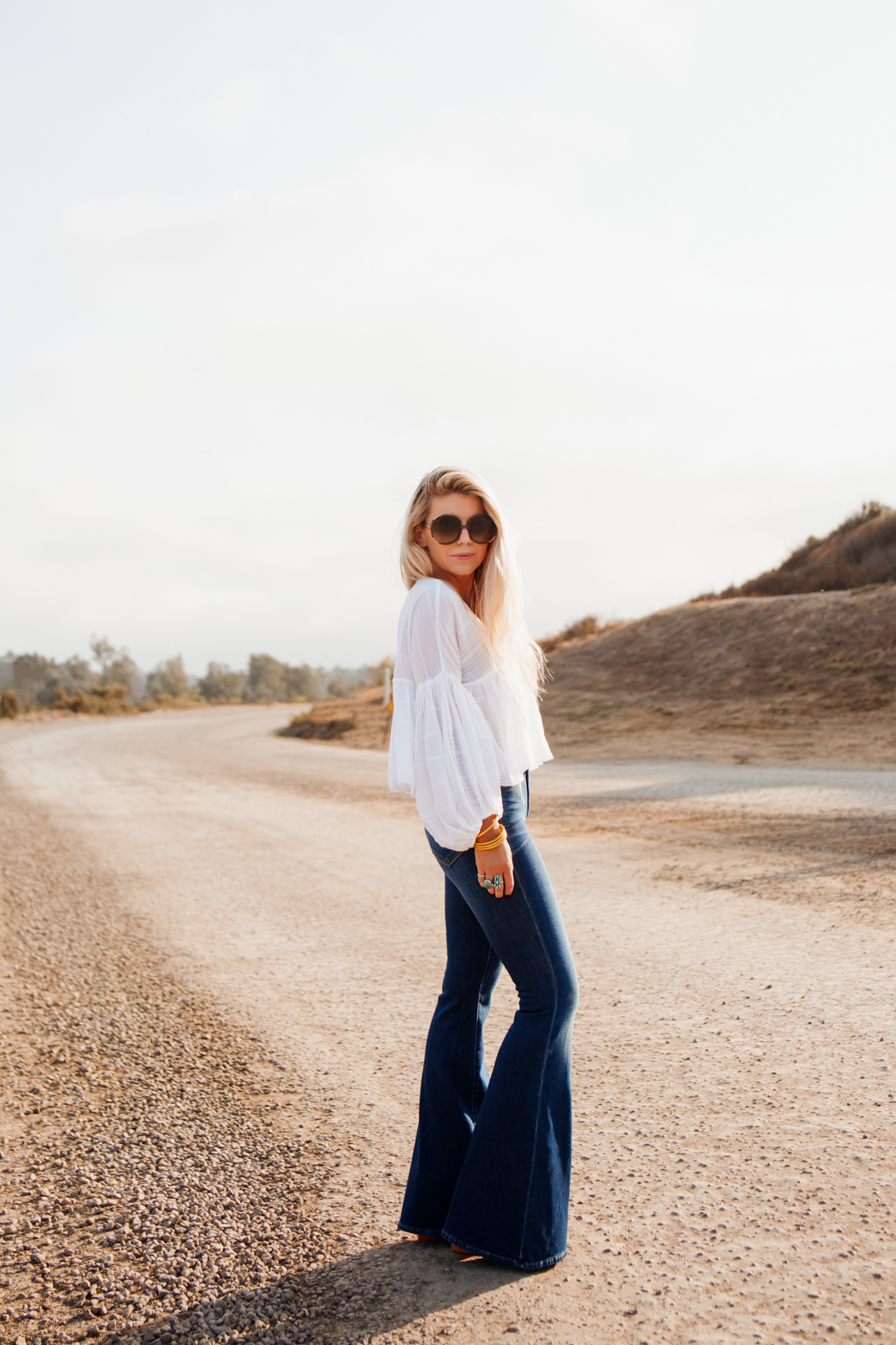 VSP Vision Care lifestyle image of woman wearing sunglasses, white blouse and jeans. 