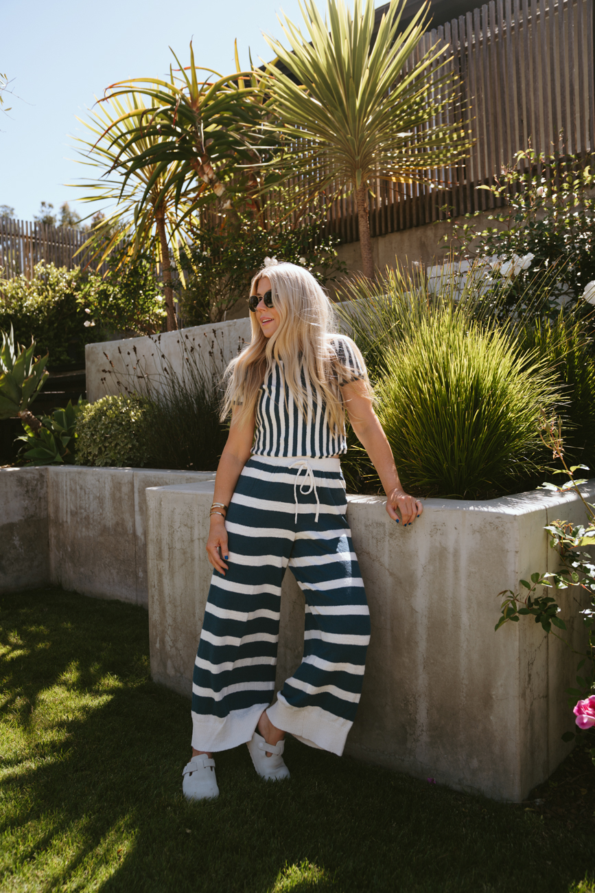 Salty Lashes Blogger Lisa Allen wearing a striped shirt and pants from Free People’s free-est Collection and sunglasses